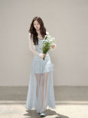 Vogsion customer wearing the Céleste light blue floral tiered tulle maxi dress with sheer skirt and romantic aesthetic for high-end summer fashion.