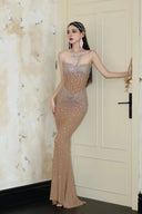 Woman in a Vogsion Sparkly Crystal Rhinestone Nude Mermaid Halter Prom Dress standing in a room with decorative walls.