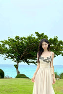 Woman in Vogsion "Lucienne" Ethereal Tulle & Contrast Lace-Inset Midi Dress standing in a grassy area with trees and water in the background