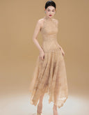 Woman wearing the Vogsion Anabeila Ethereal Sculptural Lace Halter Midi Dress in Beige against a beige background
