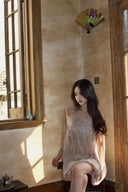 Vogsion Neutral Draped Glossy Mini Dress - A high-shine champagne off-the-shoulder dress with sculptural draping and cape sleeves worn by a Vogsion customer