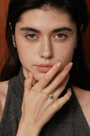 Woman wearing a Vogsion Darcy Reverie Oval Gemstone Pendant Necklace, posing with hand near face.