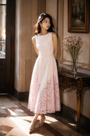 Elegant pink midi wedding guest dress with delicate lace hem and fitted waist photographed inside a luxury European hotel