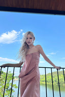 Woman in a Vogsion Strapless Twist Knot Satin Draped Maxi Dress standing on a balcony with a scenic view of trees and water.