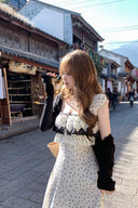 Woman in a polka dot Vogsion lace-trim ruffle maxi dress standing on a street with traditional buildings and mountains in the background.