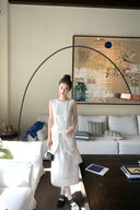 Woman in a Vogsion Shush TrongWhite Linen Statement Bow Petite Midi Dress standing in a modern living room with a large abstract painting on the wall.