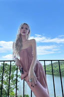 Woman in a Vogsion Strapless Twist Knot Satin Draped Maxi Dress standing on a balcony with a scenic background