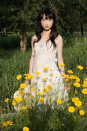 Woman in a Vogsion Odette ethereal 3D floral watercolor mesh maxi dress standing among yellow flowers in a natural setting