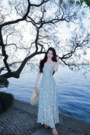 Woman in a Vogsion Light Blue Floral Maxi Dress standing by a body of water with trees in the background