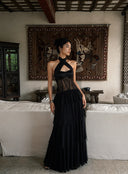 Model wearing the Vogsion Nocturne black lace corset tiered ruffle maxi dress in a front full-body view, featuring a sculpted halter neckline, sheer lace bodice, layered chiffon skirt and elegant wedding guest styling.