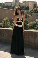 Full-length front view of VOGSION Riviera Muse deep V halter black maxi dress with nautical white trim, flowing skirt and sophisticated resort styling.