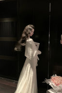 Woman in a white dress holding a bouquet of flowers in a dimly lit room.