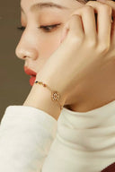 Close-up of a person wearing a gold bracelet with a neutral background