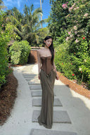 Vogsion Aphrodite Draped Set on a real customer featuring a chocolate brown lace-up corset top and moss green low-waist maxi skirt with hip cut-outs in a tropical resort setting.
