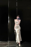 Person wearing a white satin dress standing in front of a black wall.