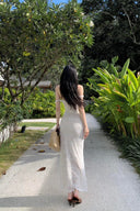 A woman modeling the Vogsion Seraphina white floral lace maxi dress with delicate ruffle straps and a form-fitting mermaid silhouette, perfect for a romantic vacation aesthetic.