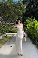 A woman modeling the Vogsion Seraphina white floral lace maxi dress with delicate ruffle straps and a form-fitting mermaid silhouette, perfect for a romantic vacation aesthetic.