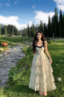 Vogsion Ethereal Meadow tiered cream maxi dress with black lace and pearl detailing worn in a scenic mountain forest meadow with horses.