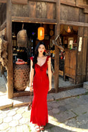 Vogsion real customer (not a professional model) wearing the Poppy Red Ruffle Maxi Dress in a rustic scenic setting — body-hugging red maxi dress with ruffle straps and plunging V-neckline
