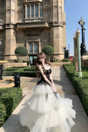 Woman in a black and white dress standing in front of an architectural building.