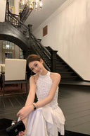 Vogsion Luna Blossom Tiered Ruffle Halter Dress in white with 3D floral appliqué and cascading ruffle tiers – worn by real everyday customer on elegant staircase, authentic fit and styling, 2026 wedding guest dress trend