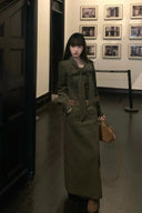 Model in moss green belted corduroy maxi dress with bow tie neckline, styled as an elegant autumn long dress, sophisticated fall to winter transitional fashion outfit.