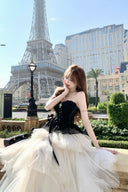 Woman in a black and white dress standing in front of the Eiffel Tower.