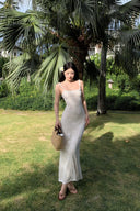 A woman modeling the Vogsion Seraphina white floral lace maxi dress with delicate ruffle straps and a form-fitting mermaid silhouette, perfect for a romantic vacation aesthetic.