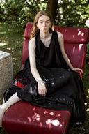 Woman in a black dress sitting on a red chair outdoors