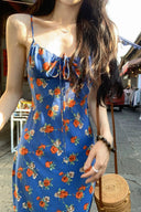 Close up detail of blue slip dress with red floral embroidery pattern and adjustable tie front neckline, lightweight bohemian summer maxi dress for vacation style.