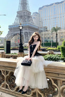 Woman in a black and white dress sitting on a ledge with the Eiffel Tower in the background