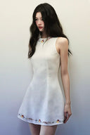 Side profile of woman in Vogsion embroidered linen mini dress, showing flattering A-line shape and embroidered hem with flowers and vines.