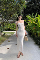 A woman modeling the Vogsion Seraphina white floral lace maxi dress with delicate ruffle straps and a form-fitting mermaid silhouette, perfect for a romantic vacation aesthetic.