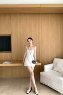 Vogsion 3D Floral Rose Embroidered White Mini Dress on real customer in modern home setting, spaghetti strap little white dress for bridal shower rehearsal dinner party, floral embroidered mini dress with black chain bag