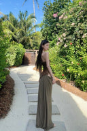 Vogsion Aphrodite Draped Set on a real customer featuring a chocolate brown lace-up corset top and moss green low-waist maxi skirt with hip cut-outs in a tropical resort setting.