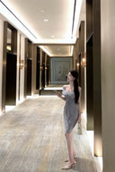 Vogsion Seraphina off-shoulder ruched gray midi dress with crystal detail in a luxury hotel hallway.