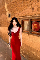 Vogsion real customer (not a professional model) wearing the Poppy Red Ruffle Maxi Dress in a rustic scenic setting — body-hugging red maxi dress with ruffle straps and plunging V-neckline