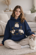 Woman wearing a navy blue hoodie with cat illustrations sitting on the floor with a cat.