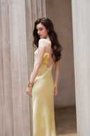 Vogsion Butter Yellow Satin Backless Slip Maxi Dress with Rosette Detail – backless doorway pose showing low scoop back and rosette appliqués