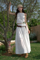 Woman in a white dress standing outdoors with trees and grass in the background