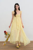 Woman wearing a yellow dress holding a floral basket against a white background