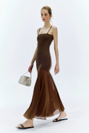 Woman wearing a brown dress with sheer overlay on a white background