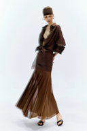 Woman wearing a brown outfit with a sheer skirt on a white background
