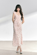 Woman wearing a light pink dress with floral patterns on a white background