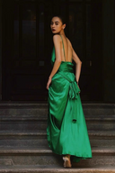Woman in a green dress standing on steps with a dark background