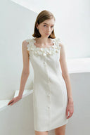 Woman wearing a white dress with floral details against a plain background