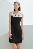 Black dress with white floral details worn by a model against a plain background