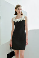 Woman wearing a black dress with white floral details against a white background