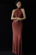 Woman wearing a burgundy halter neck gown against a black background