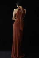 Woman wearing a long brown dress with a halter neck design on a black background